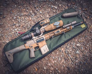 An AR15 with a Reptilia optics mount laying on a green Reptilia Rifle Case